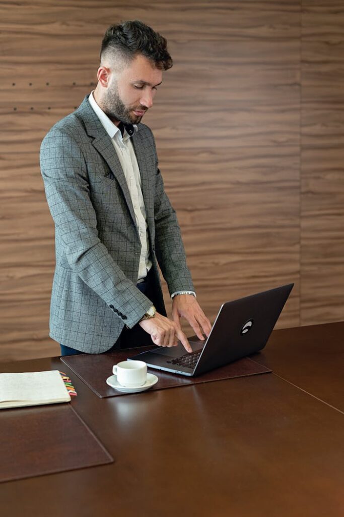 Professional man in suit working on a laptop at a modern office desk.